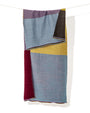 se exhibe extendido en vertical el Foulard Blok Pastel, apreciando la distribución de los bloques geométricos de color y las cenefas a rayas de los bordes.   