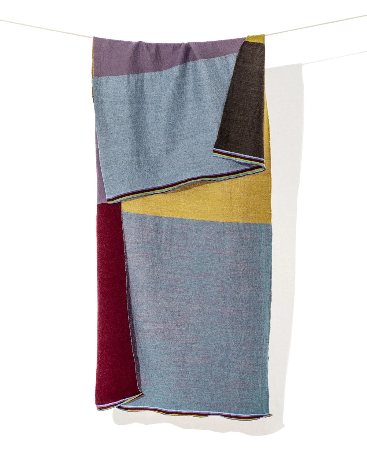 se exhibe extendido en vertical el Foulard Blok Pastel, apreciando la distribución de los bloques geométricos de color y las cenefas a rayas de los bordes.   