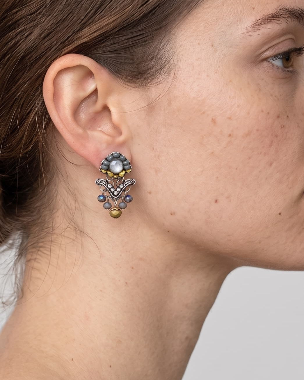 modelo luciendo uno de los pendientes articulados de Ayala Bar, mostrando su escala y cómo se asienta elegantemente sobre el lóbulo de la oreja.