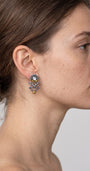 modelo luciendo uno de los pendientes articulados de Ayala Bar, mostrando su escala y cómo se asienta elegantemente sobre el lóbulo de la oreja.