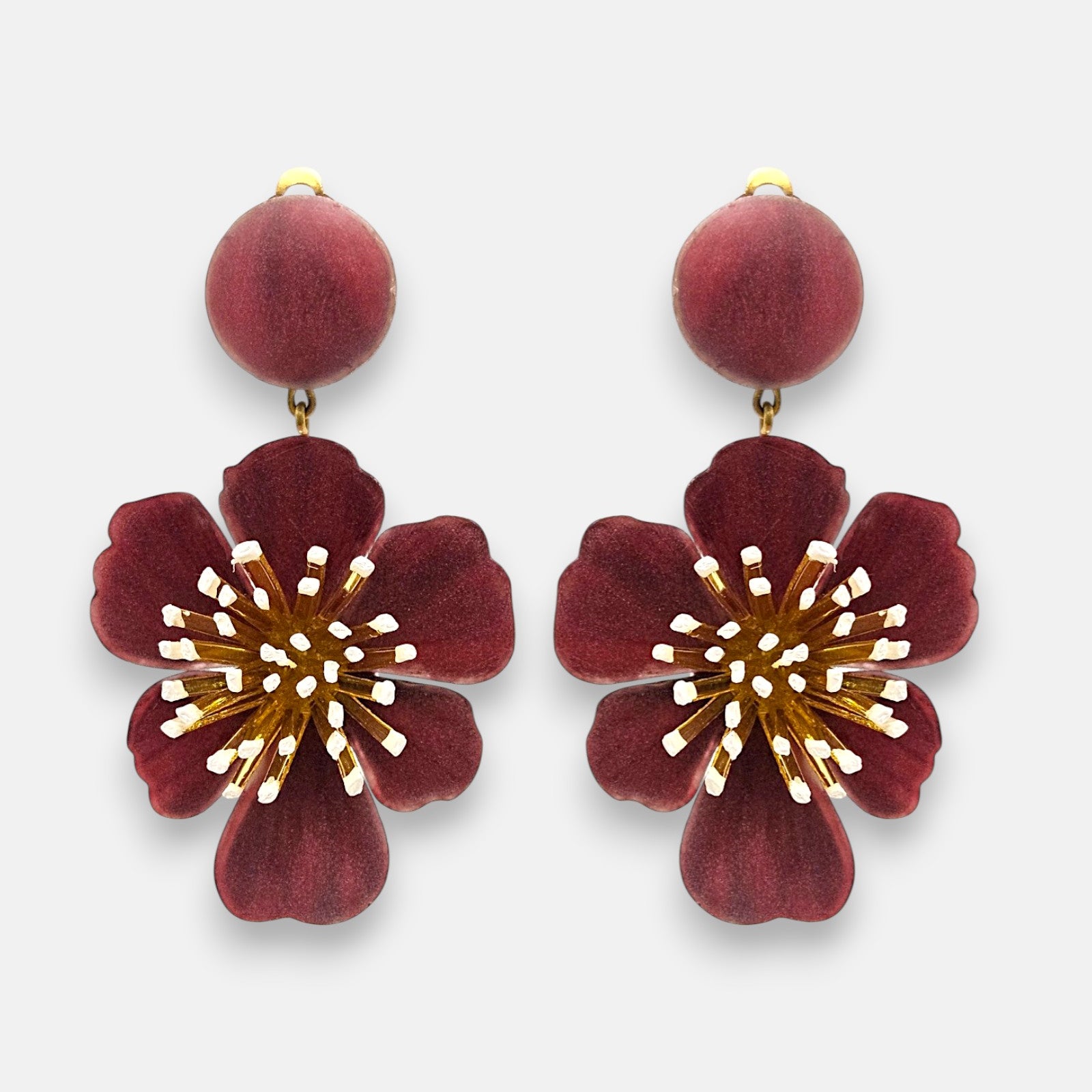 Pareja de pendientes grandes en forma de flor de Ciléa Paris, mostrando sus pétalos ondulados en color rojo guinda esmaltado y botón central a juego.