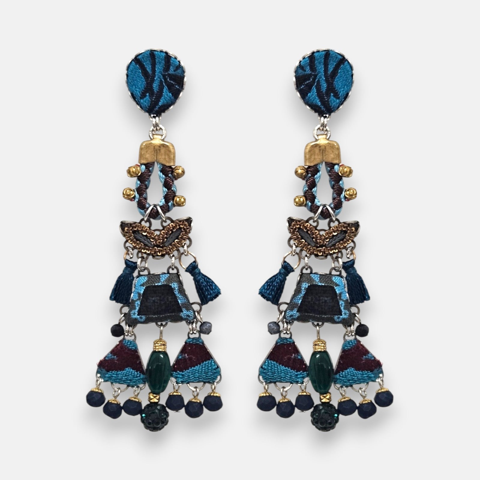 par de pendientes de frente sobre un fondo neutro, destacando su silueta alargada tipo chandelier con mosaicos en azul índigo, borlas y flecos de cuentas inferiores.