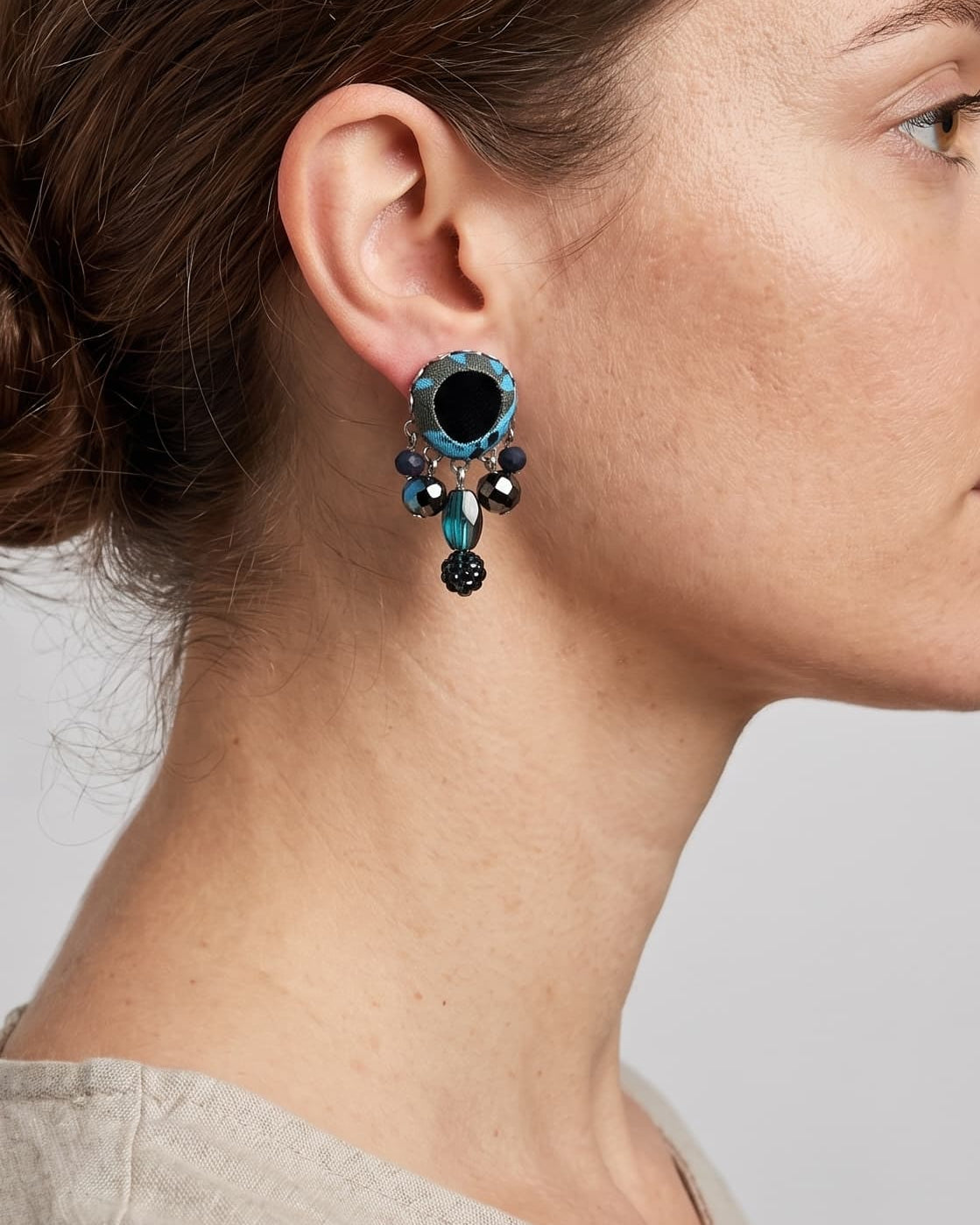 modelo de perfil luciendo uno de los pendientes de Ayala Bar, apreciando cómo asienta la pieza y el balance de sus colgantes bajo el lóbulo de la oreja.