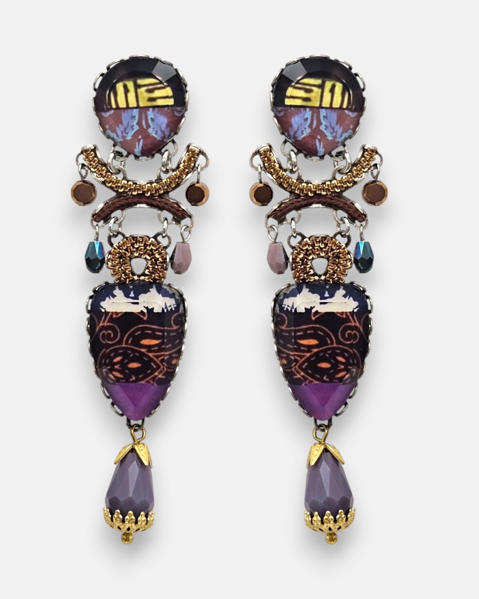 par de pendientes expuesto de frente sobre un fondo gris claro, destacando su silueta alargada de mosaico textil y la lágrima facetada malva inferior.