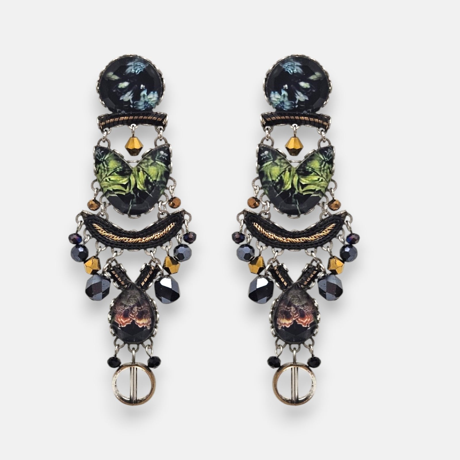 par de pendientes de frente sobre fondo claro, destacando su silueta alargada de estilo mosaico con cabujones textiles verdes y colgantes facetados.