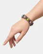 modelo luciendo la pulsera rígida articulada, destacando el relieve del cabujón verde central y cómo abraza de forma natural la muñeca.