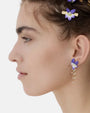 Modelo luciendo el pendiente largo de flor violeta esmaltada y cadenas de perlas de Les Néréides.