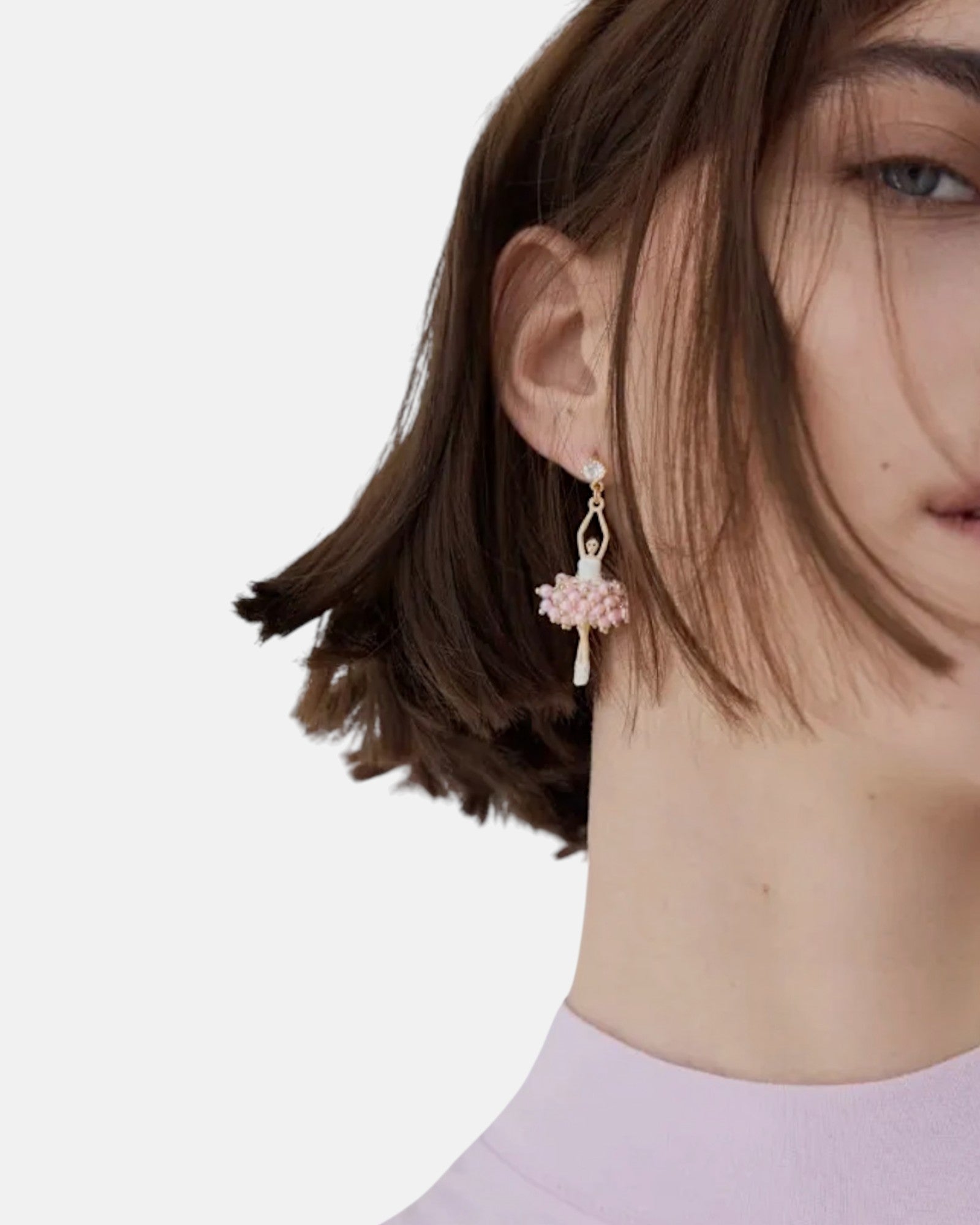 Modelo luciendo el pendiente colgante de bailarina Les Néréides con tutú de perlas rosa pastel y botón de cristal.