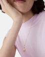 Modelo luciendo el collar fino Les Néréides Pas de Deux con colgante de bailarina en tutú rosa sobre camiseta pastel.