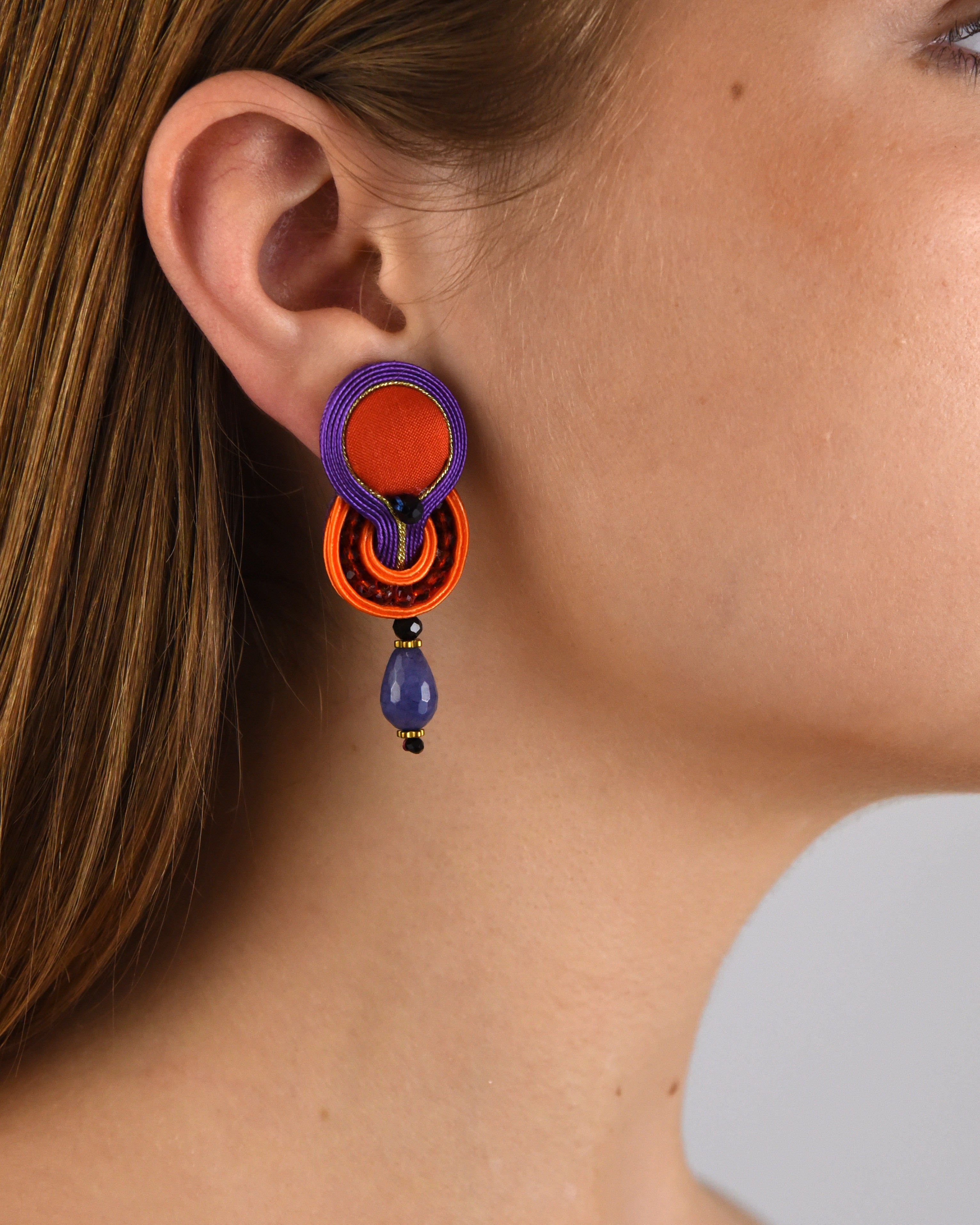 Mujer luciendo los pendientes Mini Brigitte Violet & Orange, destacando su tamaño ideal y la intensidad de sus colores.