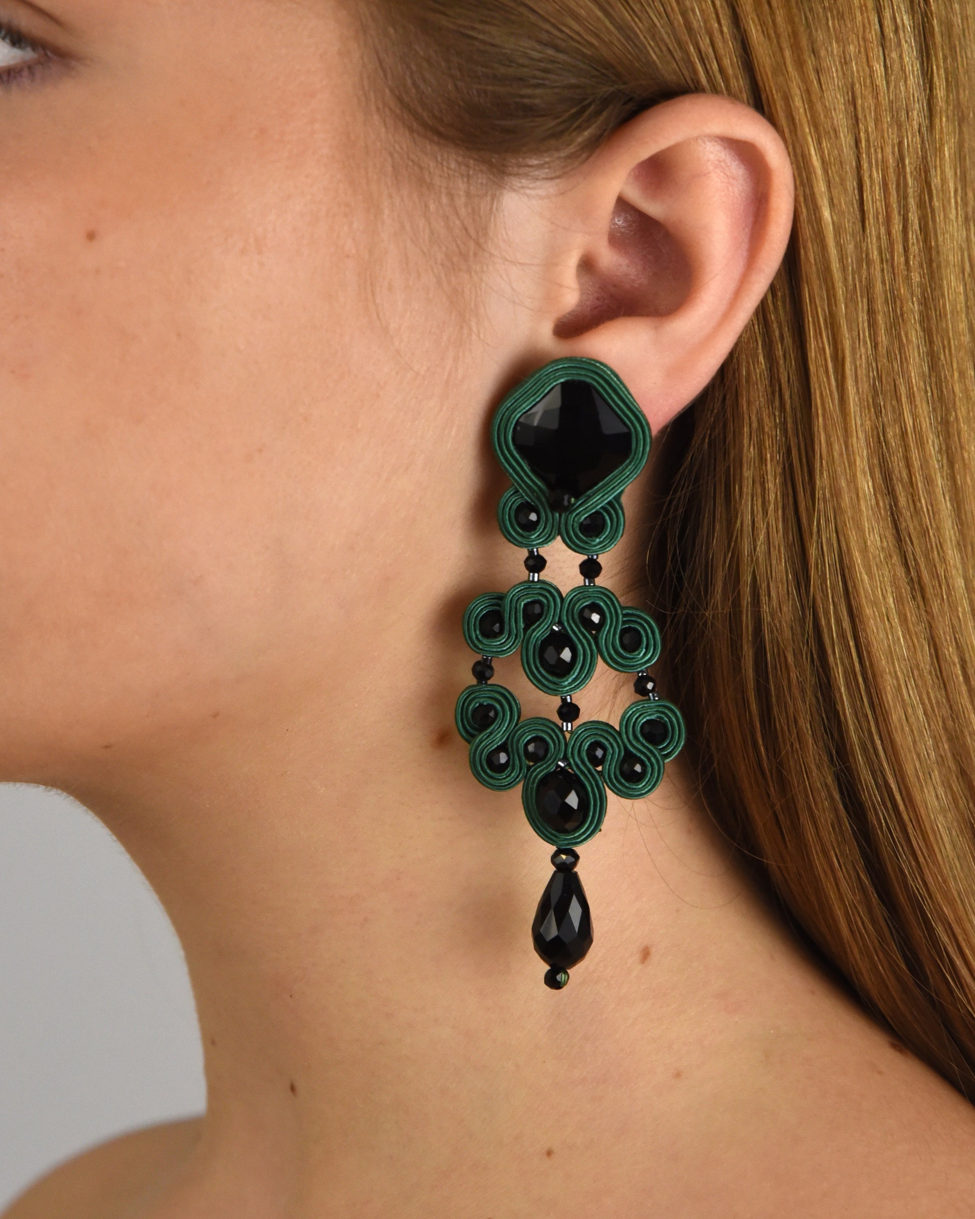 Mujer luciendo los pendientes statement Gótico Azabache Verde, resaltando su contraste con la piel y su elegancia arquitectónica