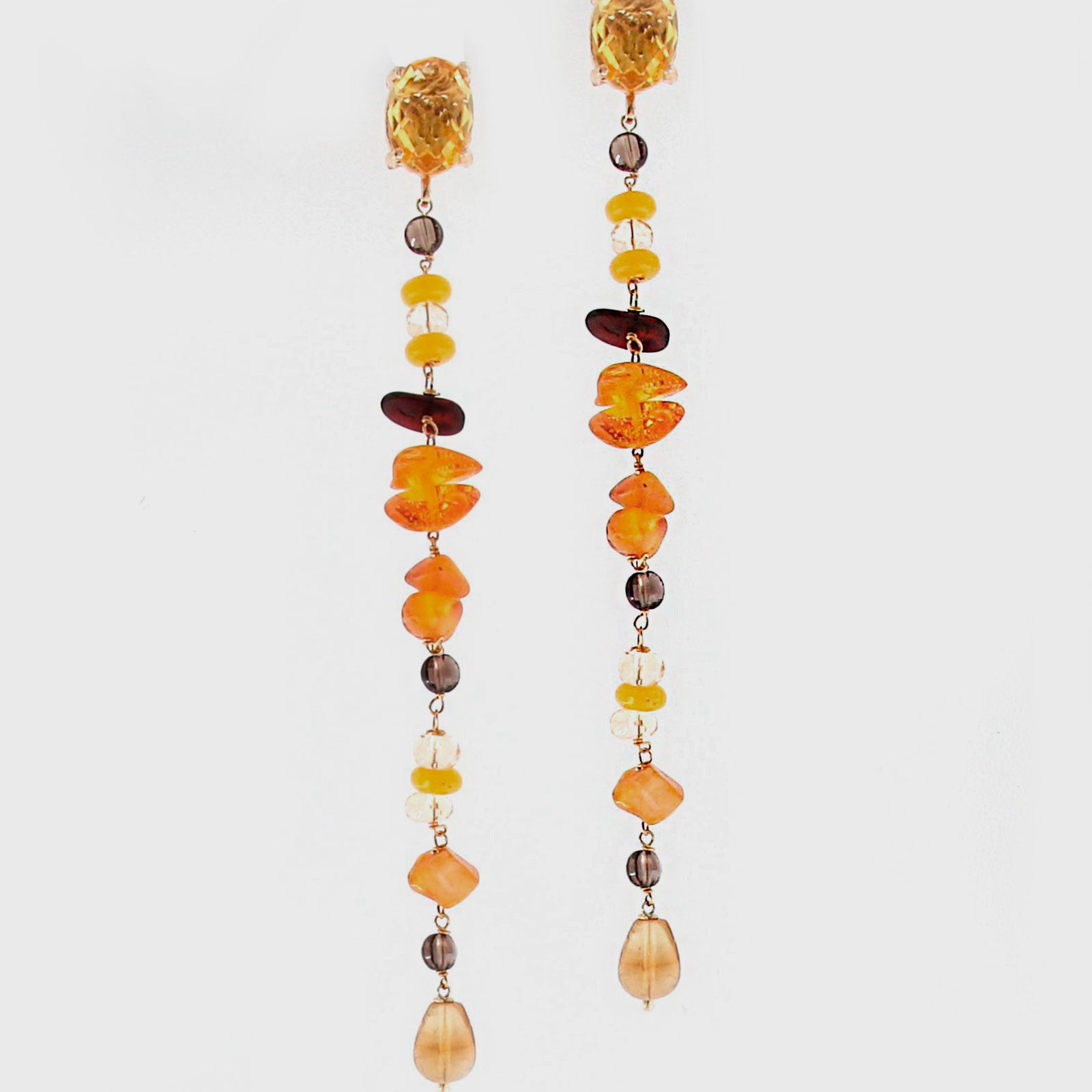Pareja de pendientes lineales Amlé con hilera de piedras naturales de ámbar, cuarzo y ágatas amarillas sobre fondo blanco.