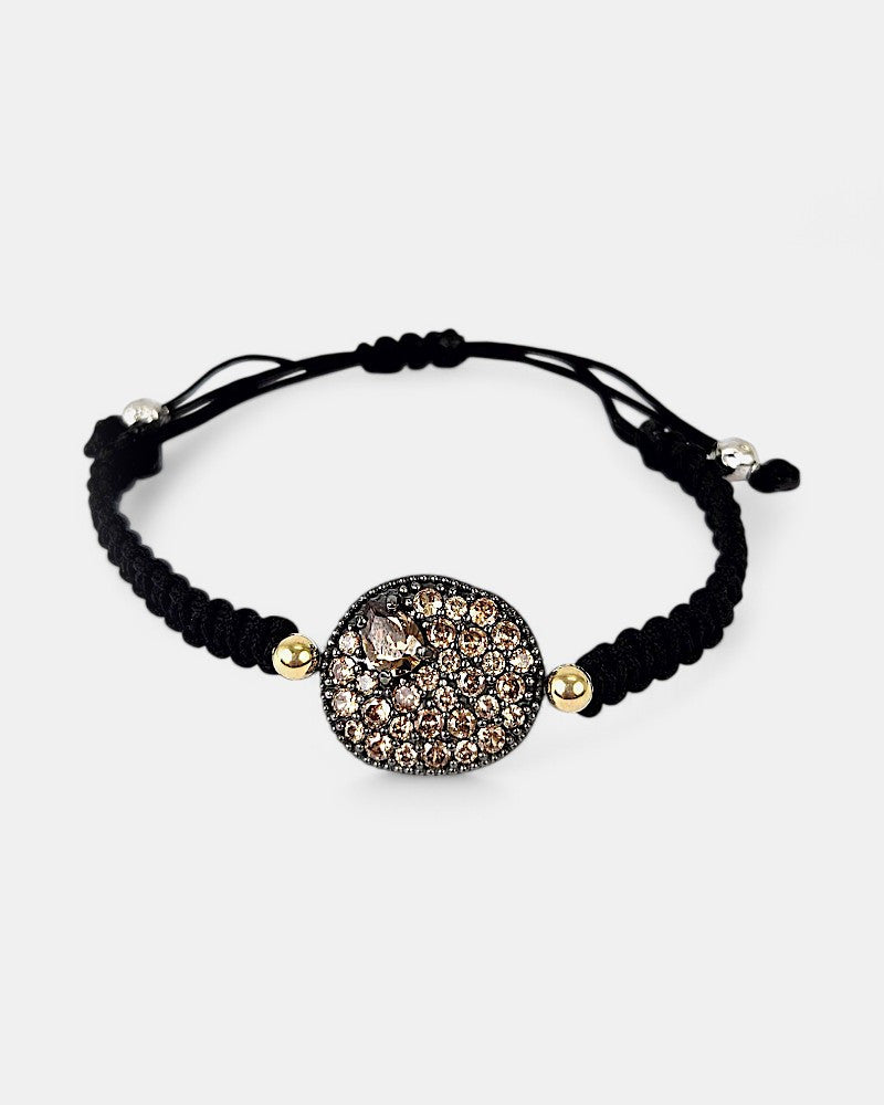 Pulsera de macramé negro Bohemme Musa con medallón central de plata oxidada y pavé de circonitas champagne.
