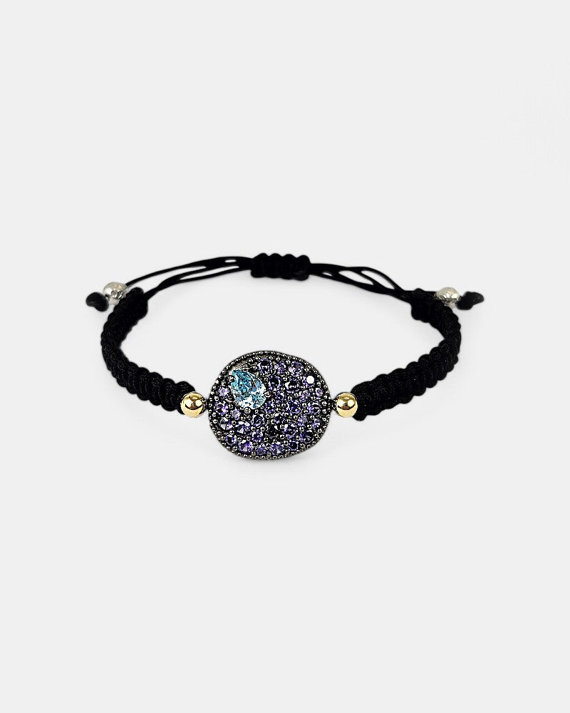 Pulsera de macramé negro Bohemme Musa con medallón de plata oxidada y pavé de circonitas violetas con detalle azul.