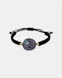 Pulsera de macramé negro Bohemme Musa con medallón de plata oxidada y pavé de circonitas violetas con detalle azul.