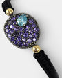 Detalle de la pulsera Bohemme Musa violeta puesta en la muñeca, mostrando su brillo y el ajuste del macramé.