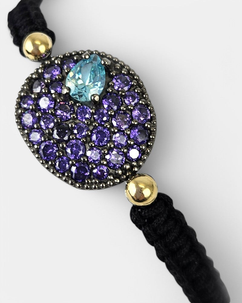 Detalle de la pulsera Bohemme Musa violeta puesta en la muñeca, mostrando su brillo y el ajuste del macramé.