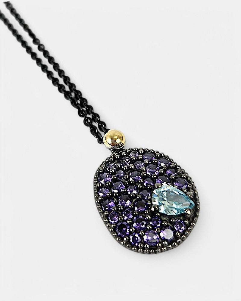 Primer plano del medallón Musa violeta mostrando el engaste de las gemas y la esfera decorativa de oro de 18K.
