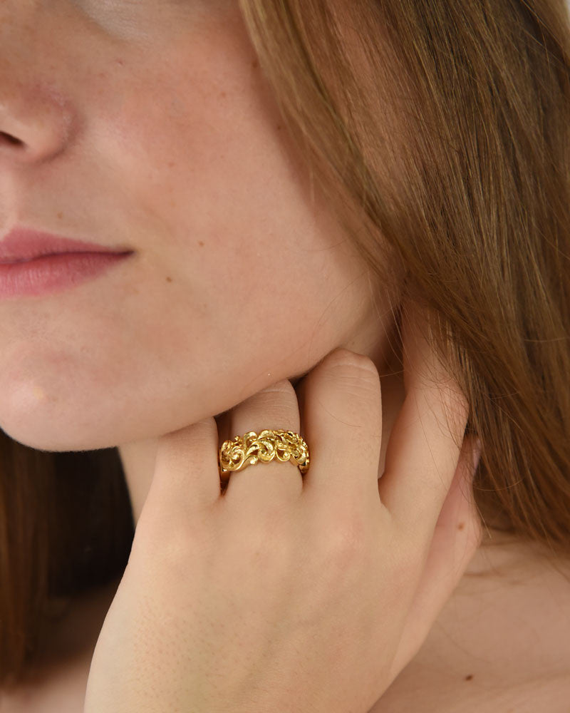 modelo luciendo el anillo Clarice en la mano, apreciando la anchura de la banda y su presencia dorada.