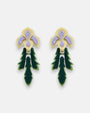 Par de pendientes "Iris" de Gissa Bicalho con diseño floral en resina crema, lila y verde sobre fondo claro.