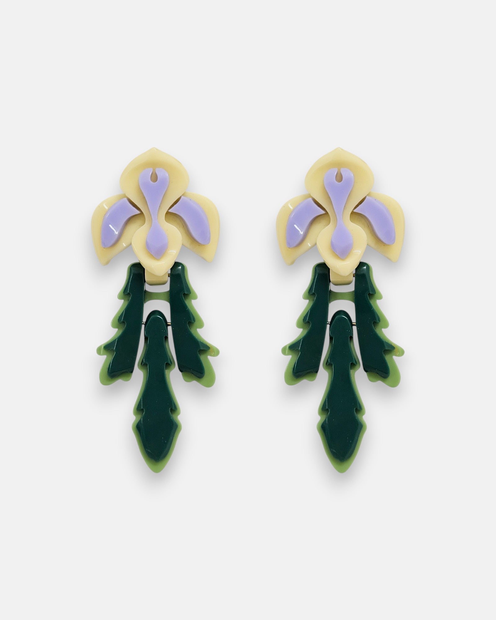 Par de pendientes "Iris" de Gissa Bicalho con diseño floral en resina crema, lila y verde sobre fondo claro.