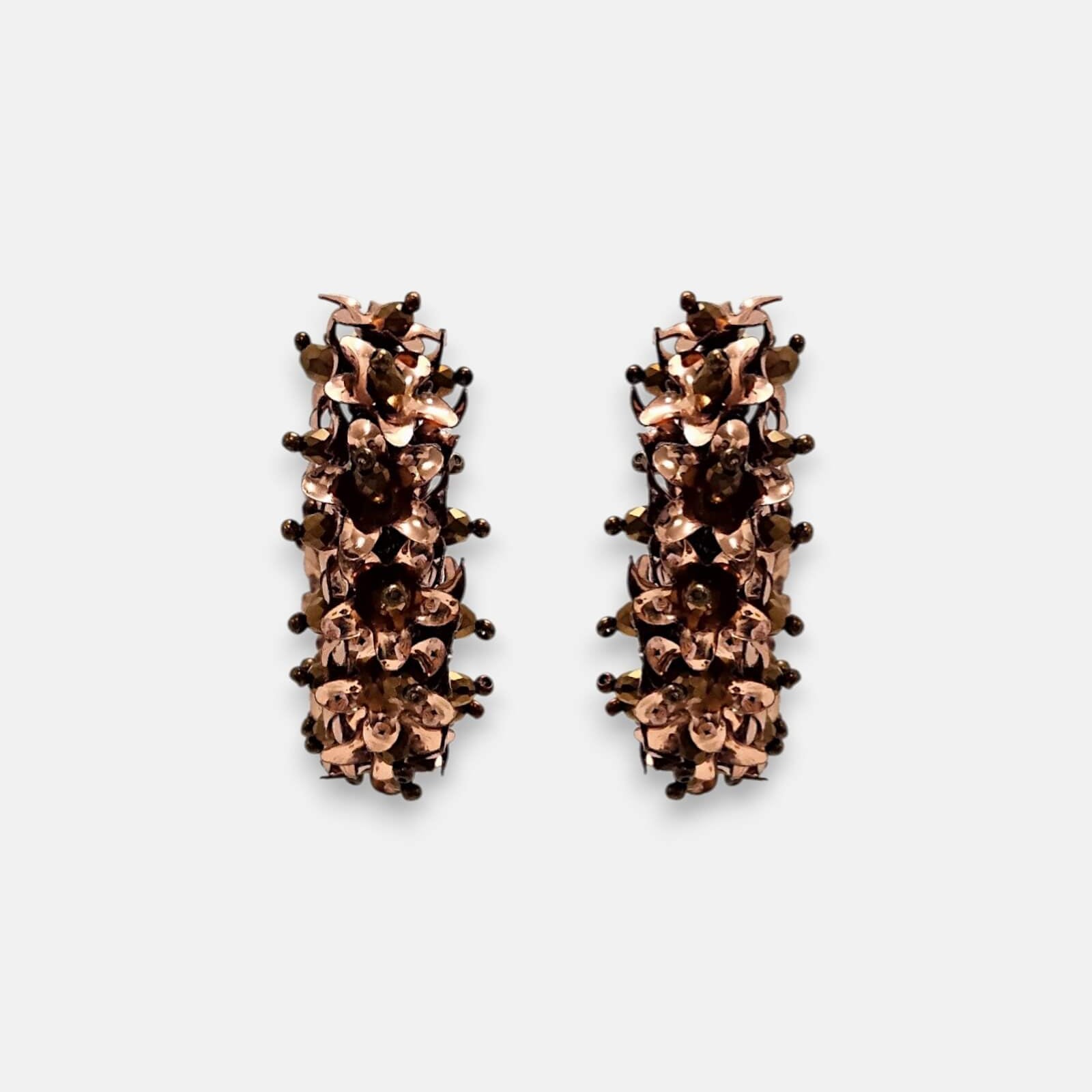 Par de pendientes de aro "Jardín de Cobre" con textura floral en relieve sobre fondo claro.