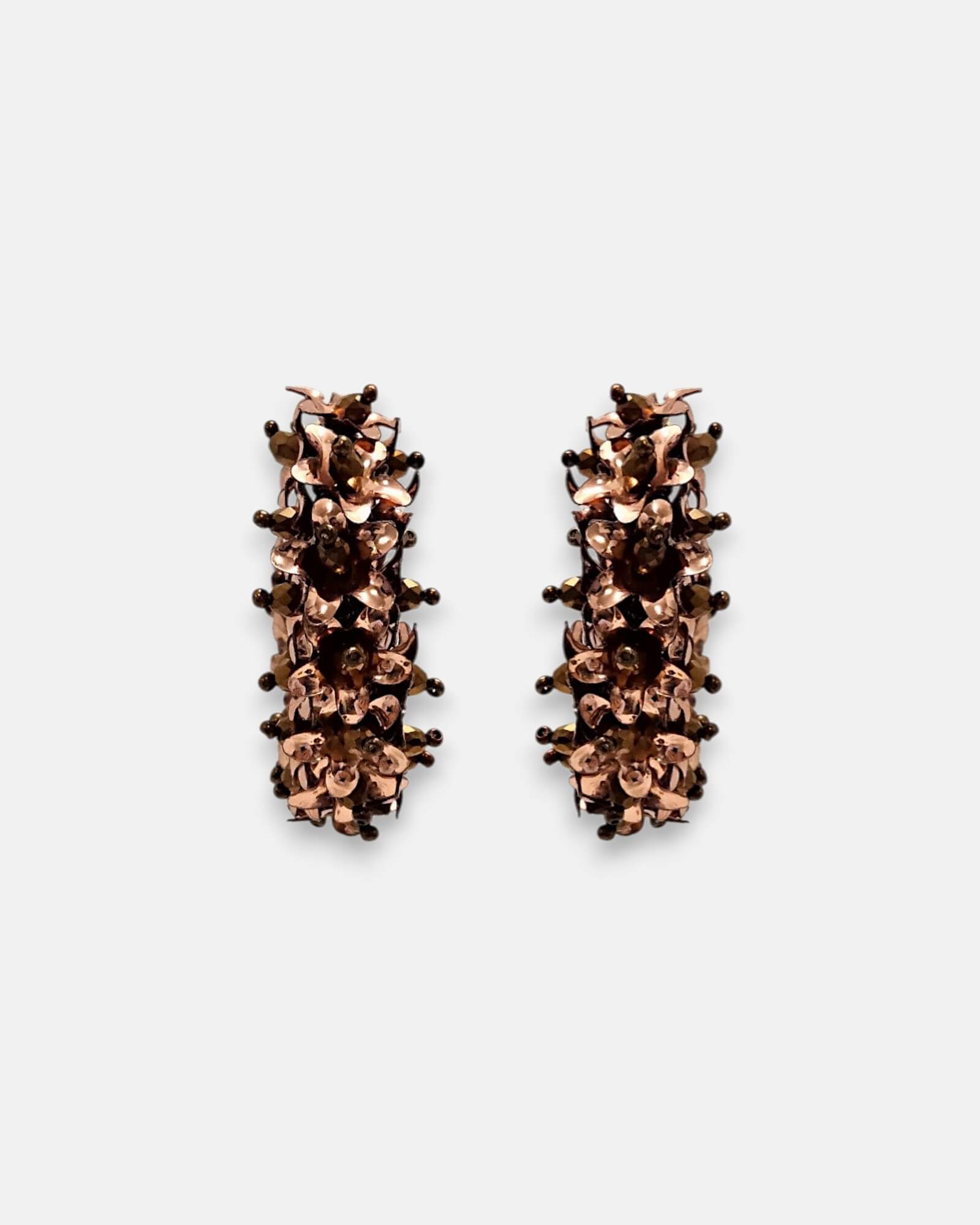 Par de pendientes de aro "Jardín de Cobre" con textura floral en relieve sobre fondo claro.