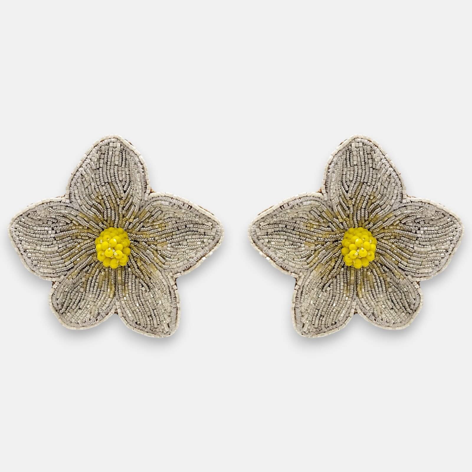Pendientes "Pétalos de Luz" con diseño floral bordado en tonos plata y centro amarillo cítrico sobre fondo claro.
