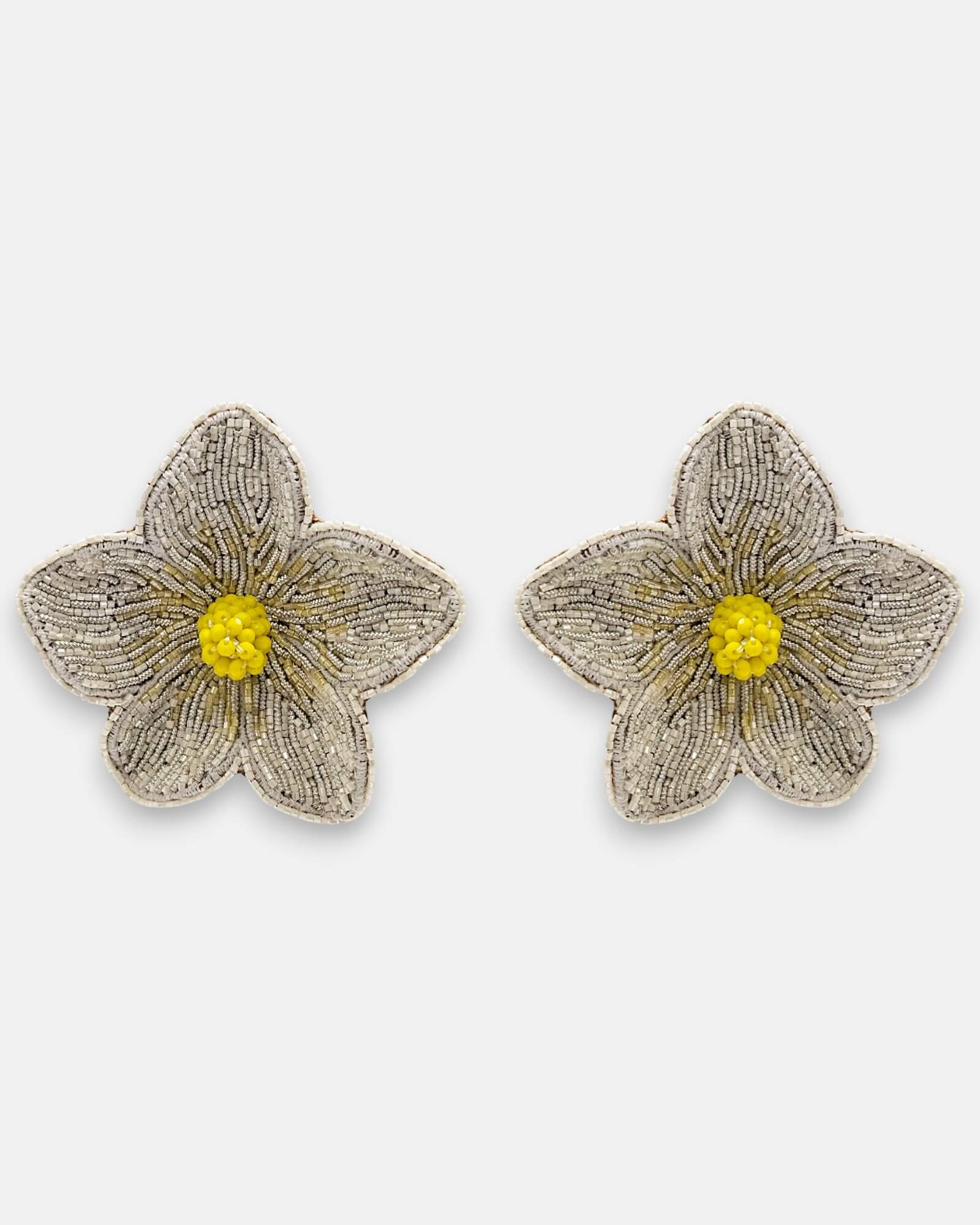 Pendientes "Pétalos de Luz" con diseño floral bordado en tonos plata y centro amarillo cítrico sobre fondo claro.