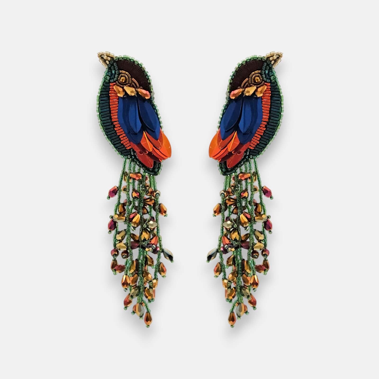 Par de pendientes "Vuelo Tropical" con diseño de ave exótica y cascada de cuentas en tonos azules y naranjas sobre fondo claro.