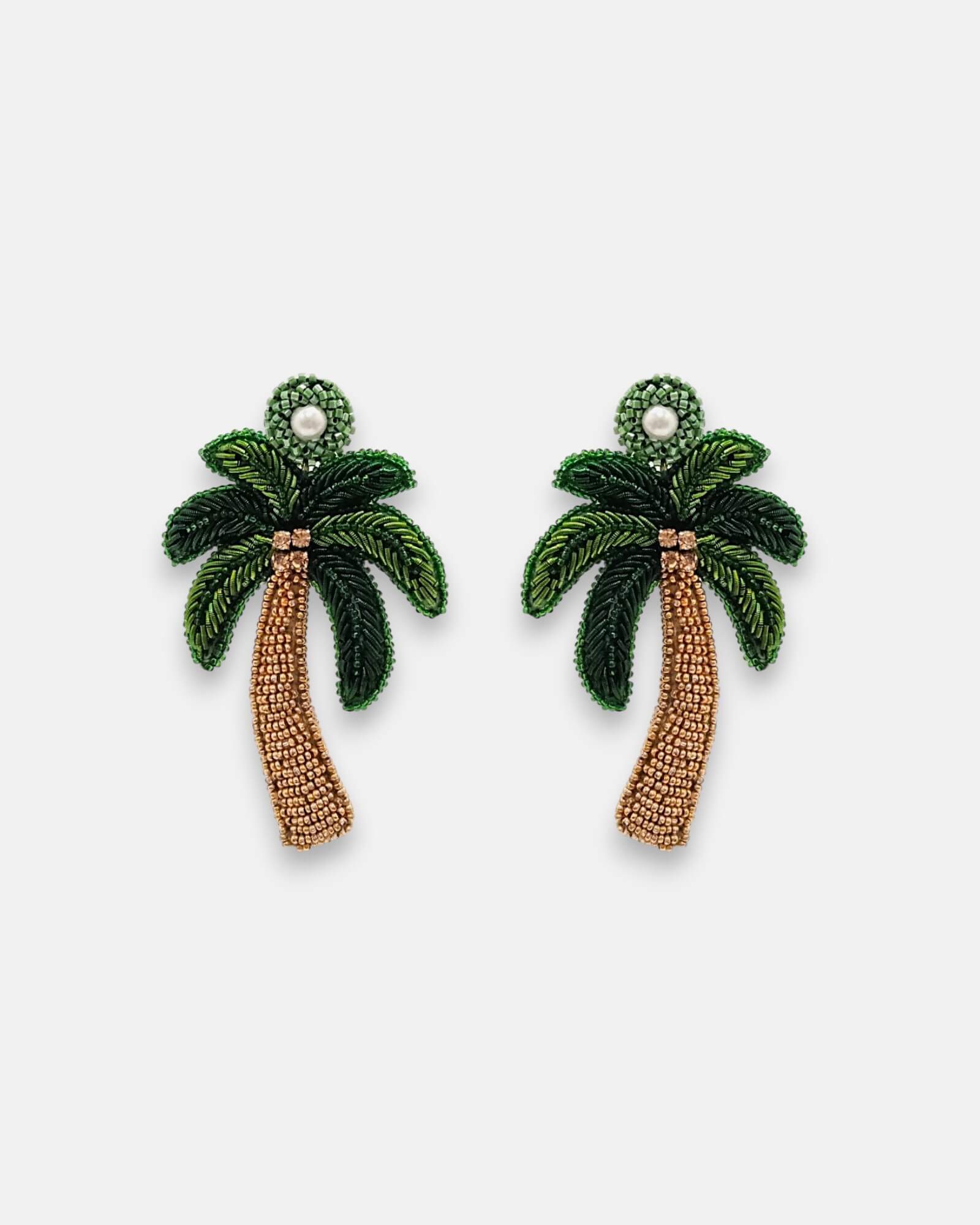 Pendientes "Oasis Tropical" con diseño de palmera bordados en pedrería verde y bronce sobre fondo claro.