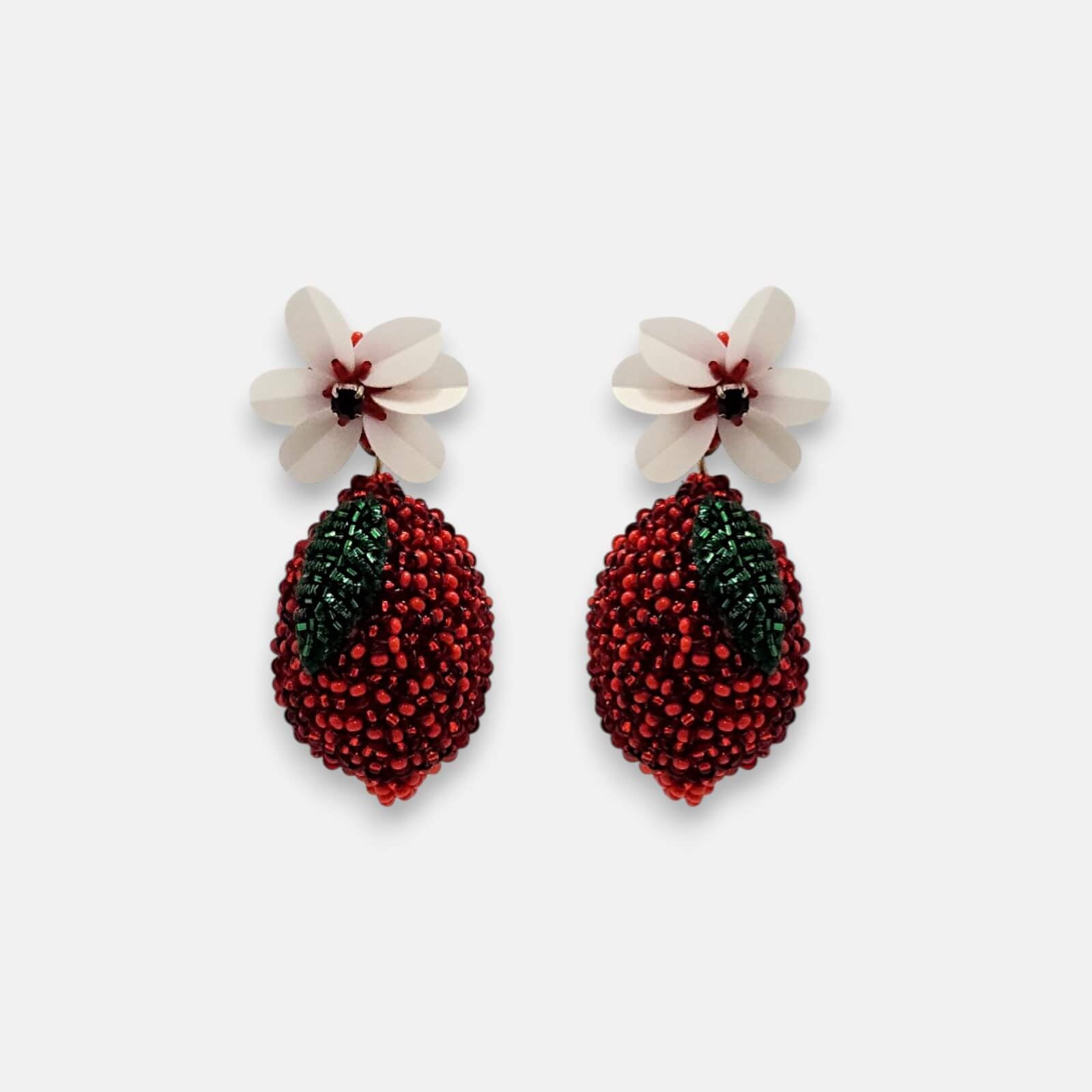 Pendientes "Fruto Prohibido" en forma de fruto rojo bordado con flor blanca superior sobre fondo claro.