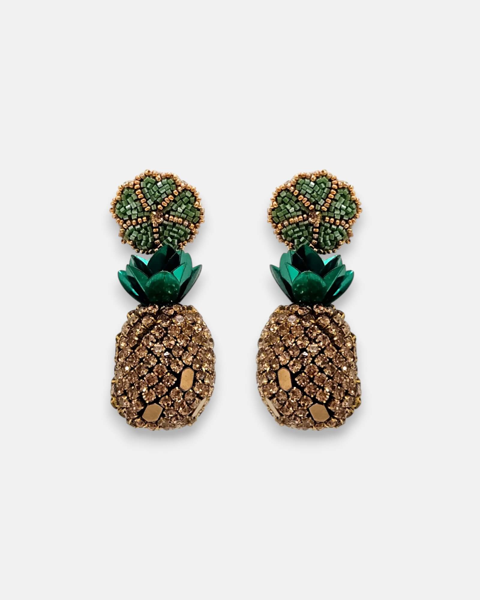 Pendientes "Bajo el Sol de Oro" con diseño de piña bordado en cristales dorados y hojas metálicas verdes sobre fondo neutro.