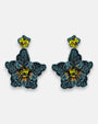 Par de pendientes "Noche de Azabache" con diseño floral bordado en tonos azul noche y centro amarillo sobre fondo neutro.