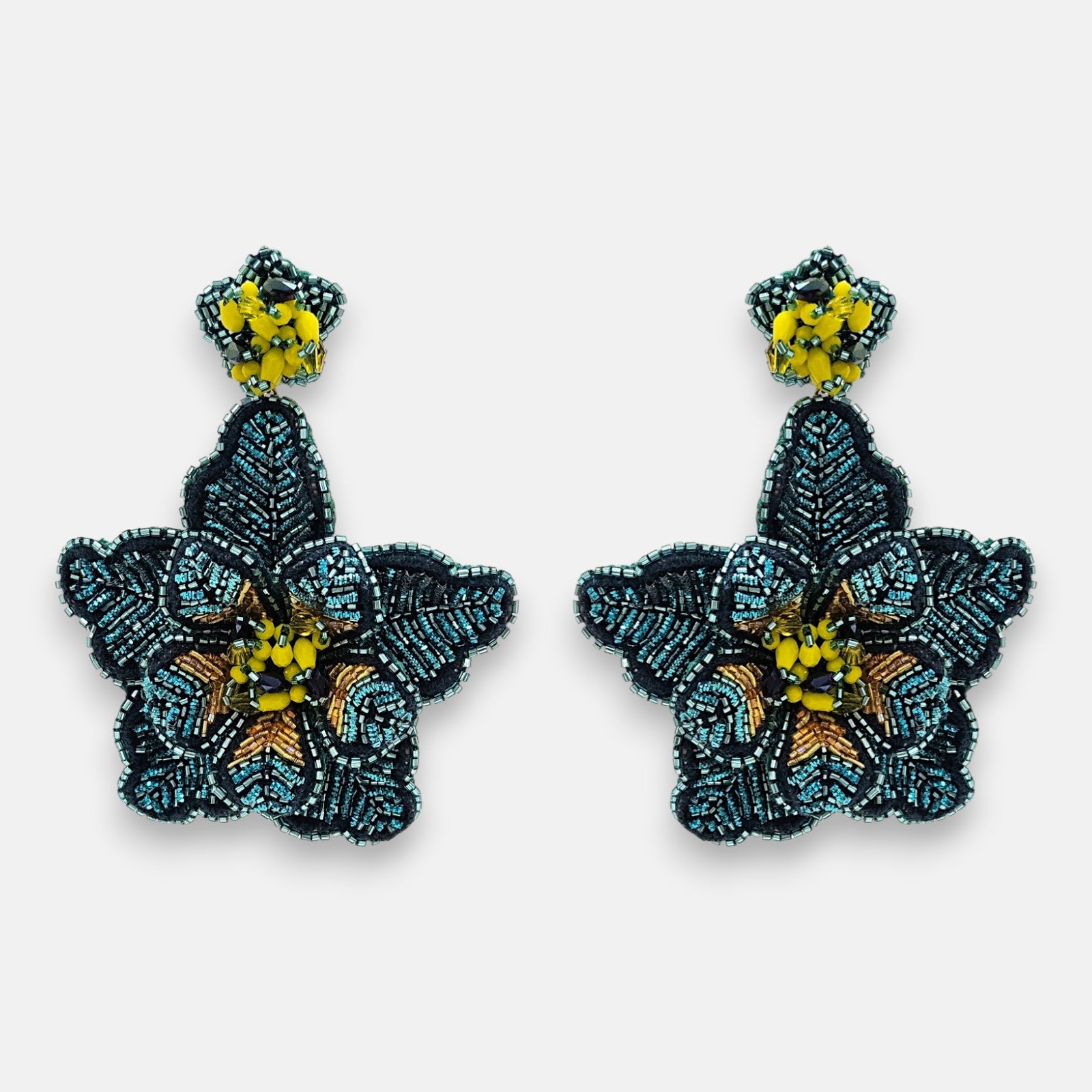 Par de pendientes "Noche de Azabache" con diseño floral bordado en tonos azul noche y centro amarillo sobre fondo neutro.