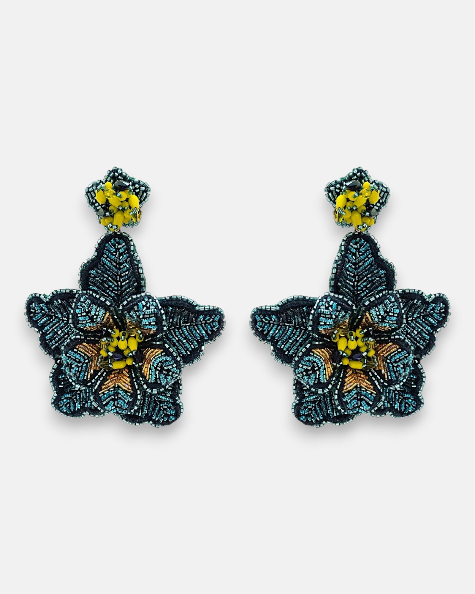 Par de pendientes "Noche de Azabache" con diseño floral bordado en tonos azul noche y centro amarillo sobre fondo neutro.
