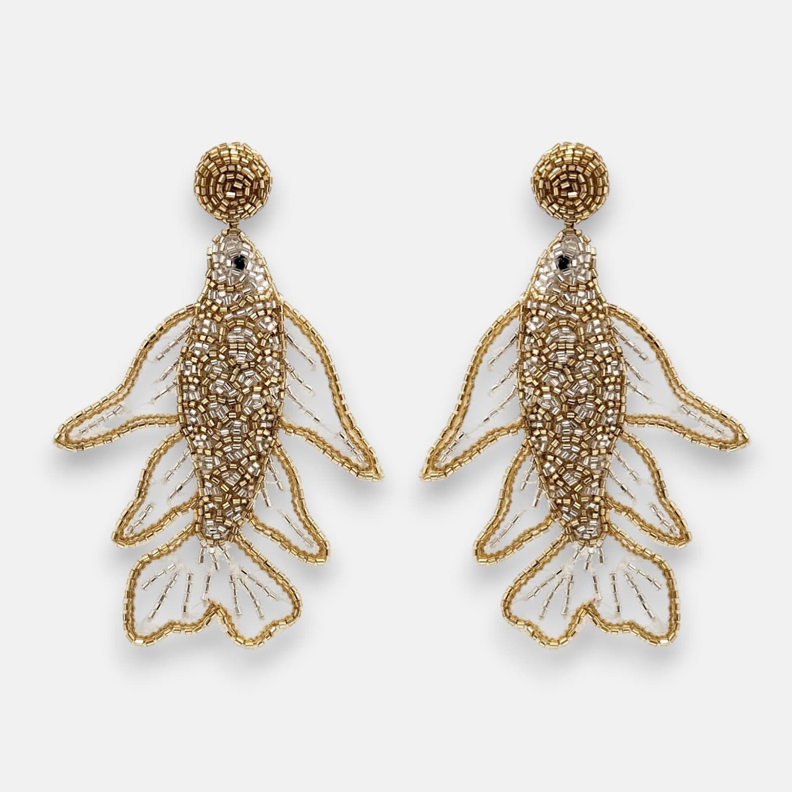 Pendientes "Danza de Oro" con diseño de pez bordado en pedrería dorada y plateada sobre tul transparente sobre fondo claro.