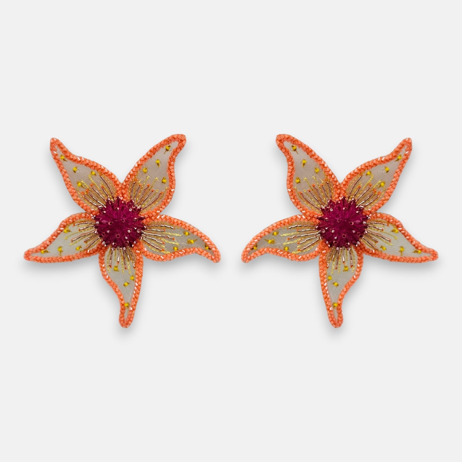 Pendientes "Jardín de Hespérides" con diseño de flor bordada sobre tul en tonos coral y centro carmesí sobre fondo claro.
