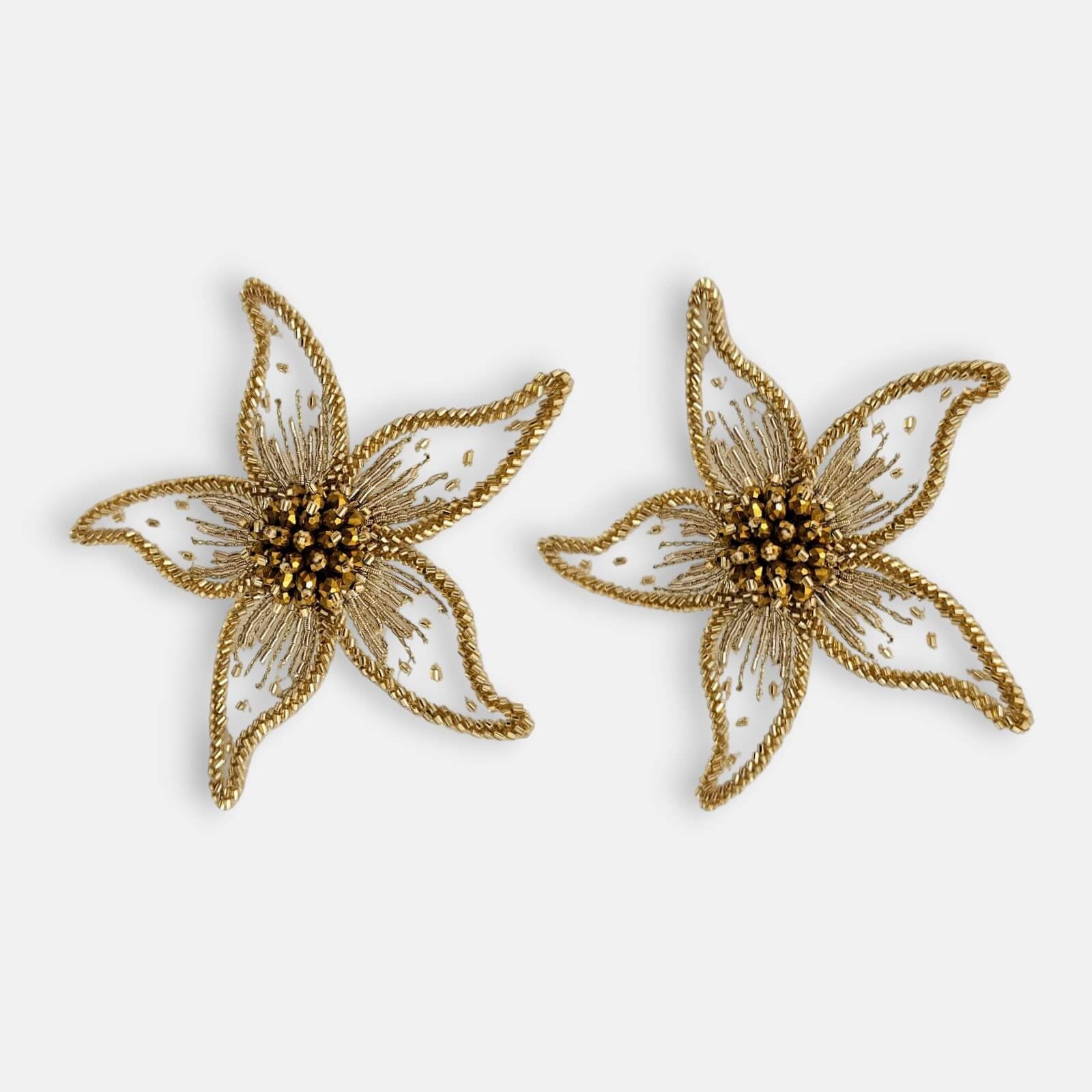 Par de pendientes "Destello Solar" con diseño de flor bordada sobre tul transparente y detalles dorados sobre fondo claro.