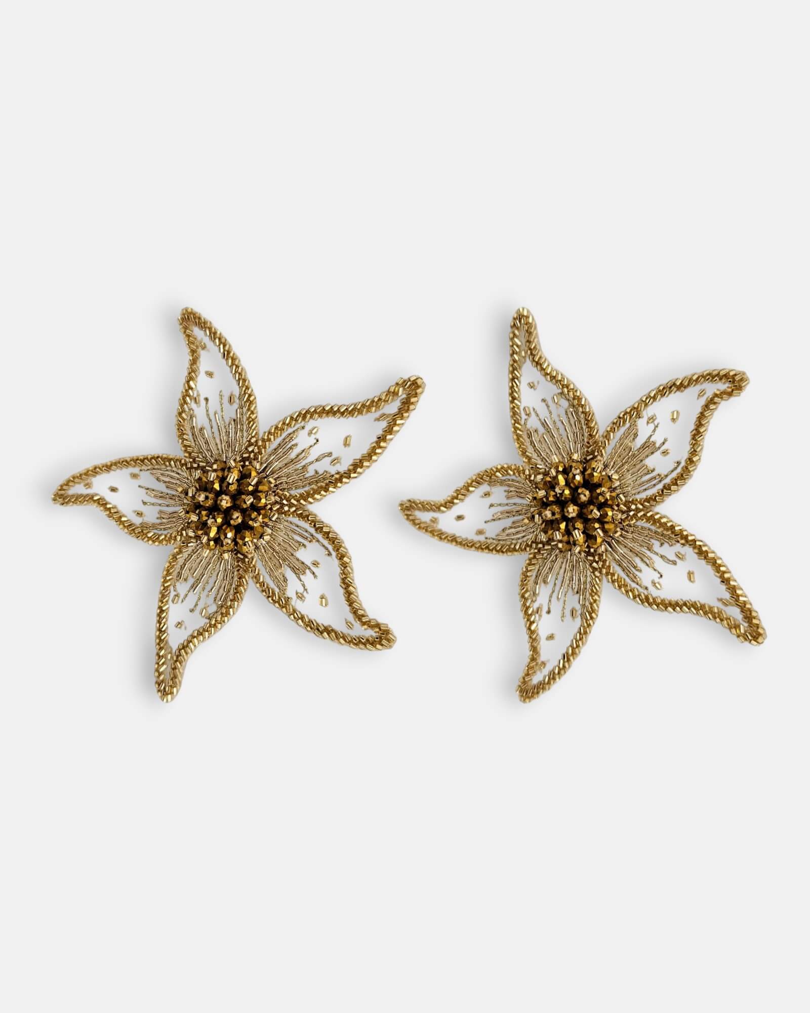 Par de pendientes "Destello Solar" con diseño de flor bordada sobre tul transparente y detalles dorados sobre fondo claro.