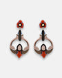 Par de pendientes "Vitraux" de Gissa Bicalho con diseño circular y trébol en resina naranja, rosa y azul sobre fondo blanco.