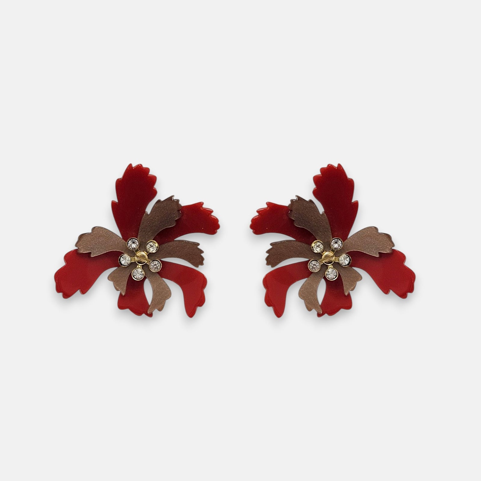 Par de pendientes "Flor de Fuego" de Gissa Bicalho con pétalos en resina roja y bronce con cristales centrales sobre fondo blanco.