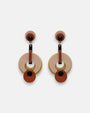 Par de pendientes "Eclipsse" de Gissa Bicalho con diseño de círculos en resina rosa, terracota y verde oliva sobre fondo claro.