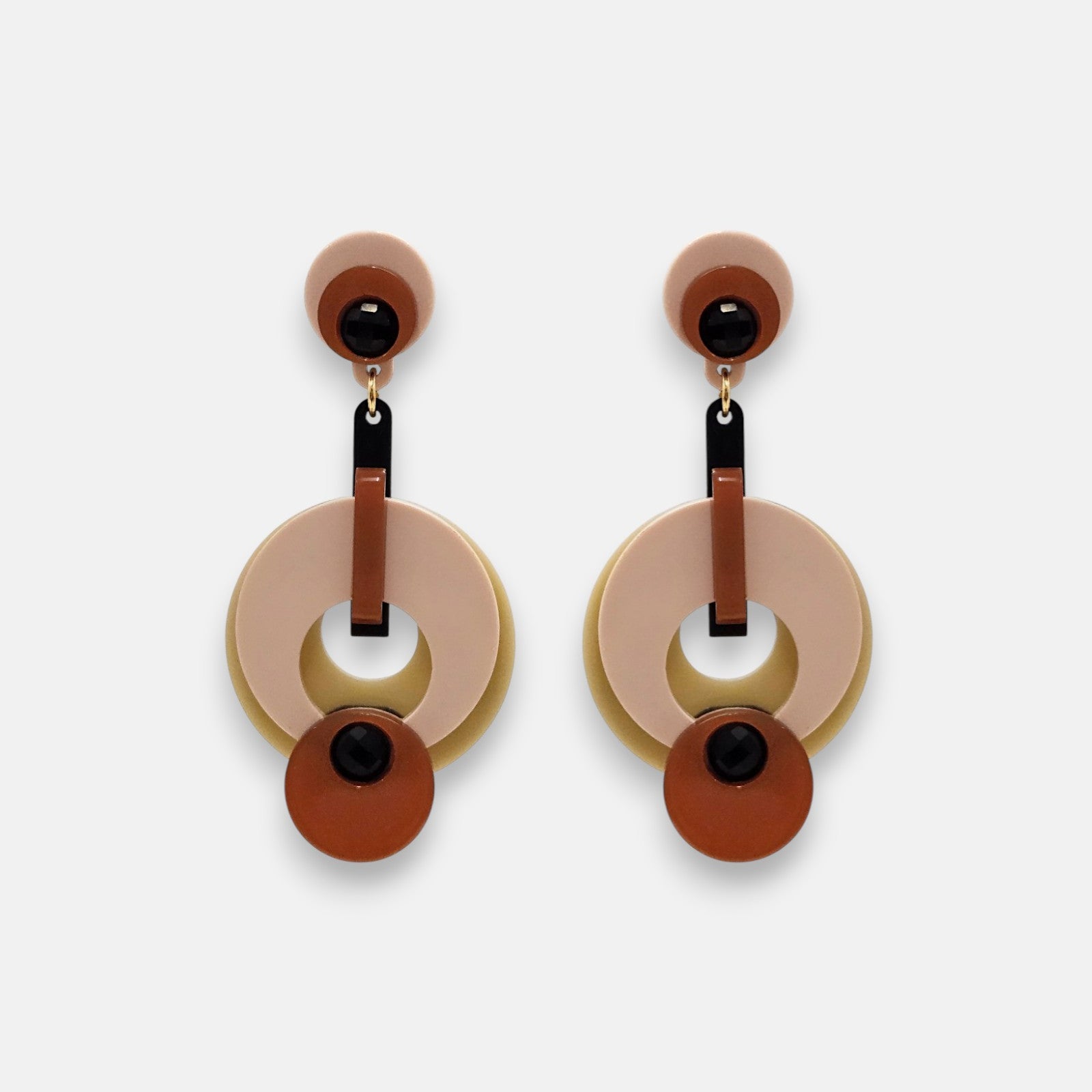 Par de pendientes "Eclipsse" de Gissa Bicalho con diseño de círculos en resina rosa, terracota y verde oliva sobre fondo claro.
