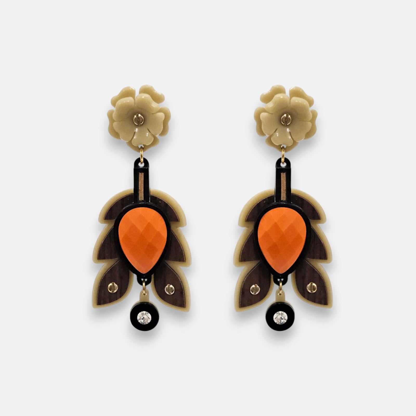 Par de pendientes "Otoño Escultórico" de Gissa Bicalho con diseño de hojas en resina arena, madera y centro naranja sobre fondo claro.