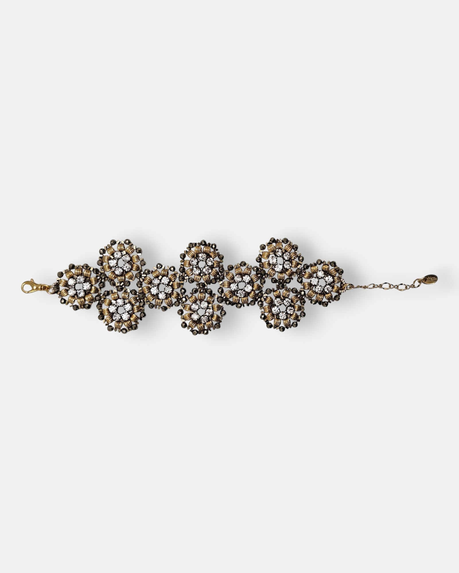 Maxi pulsera ancha Tataborello extendida compuesta por una red de rosetones florales dorados y brillantes.