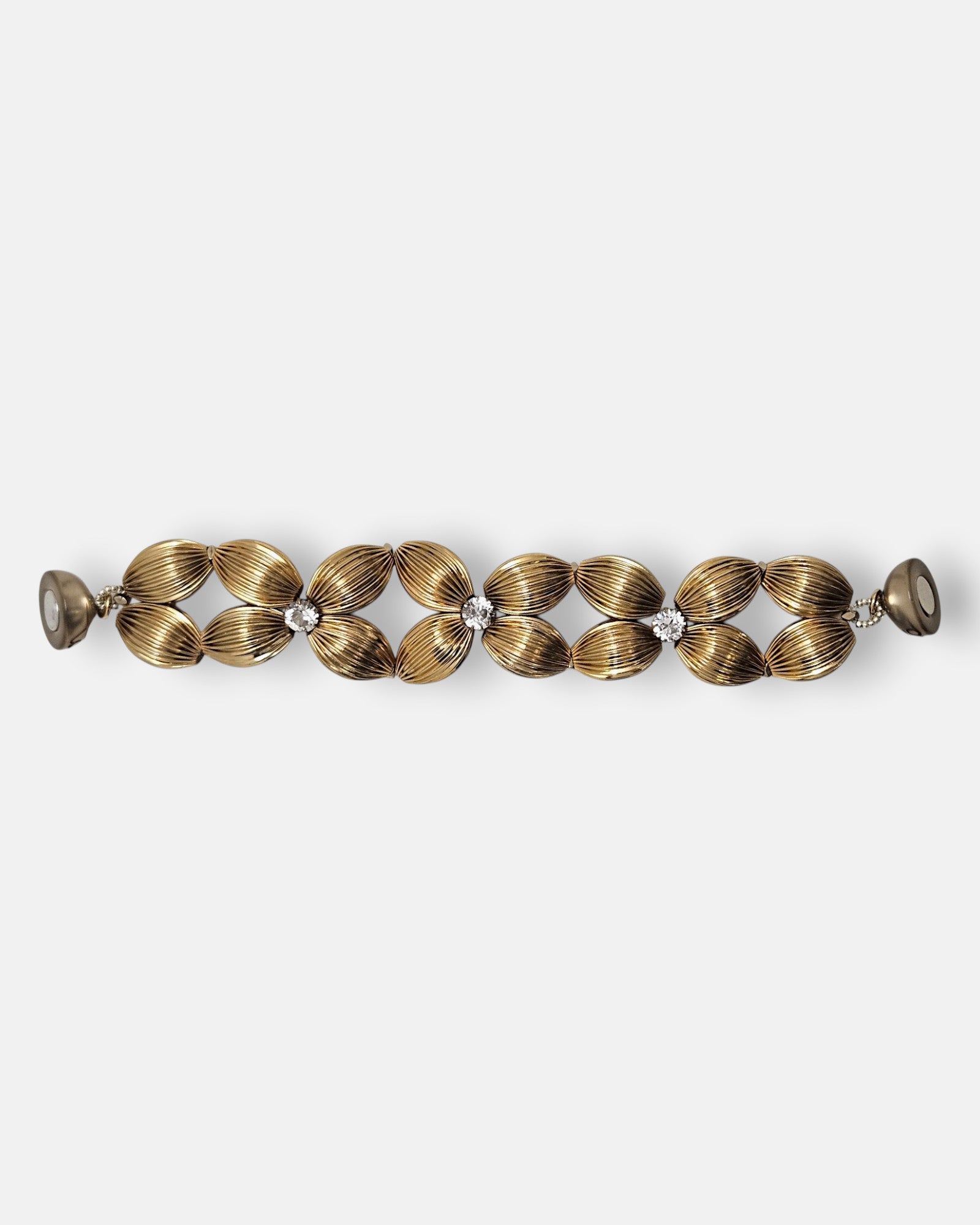 Pulsera Tataborello extendida mostrando el diseño de flores doradas y el cierre magnético en los extremos.