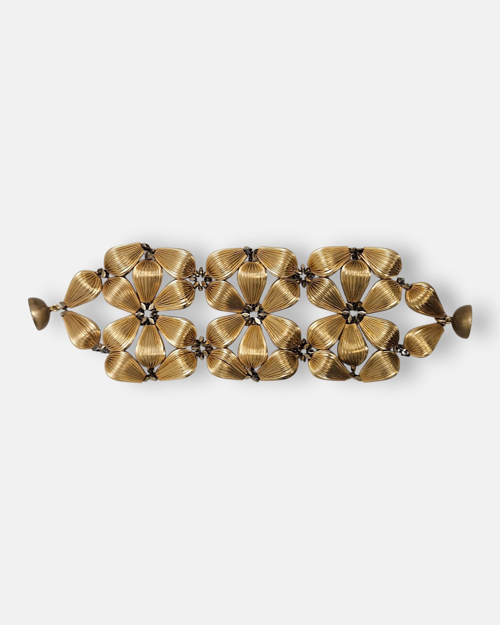 Maxi pulsera ancha Tataborello extendida con diseño calado de flores doradas estriadas y cierre magnético.