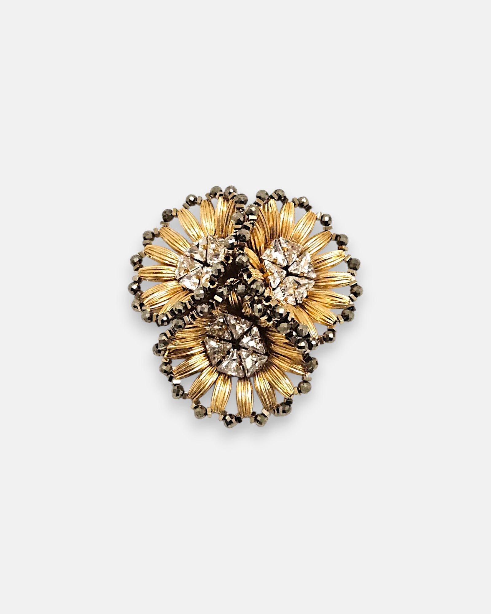 Broche de solapa maxi Tataborello compuesto por tres flores doradas estriadas con cristales en el centro.