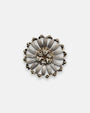 Pin broche redondo Tataborello con diseño de flor calada en rutenio plateado y cristales centrales.